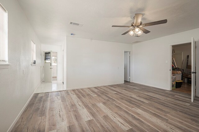 unfurnished bedroom with ceiling fan, wood finished floors, visible vents, and baseboards