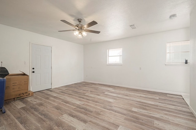 spare room with a ceiling fan, visible vents, baseboards, and light wood-type flooring