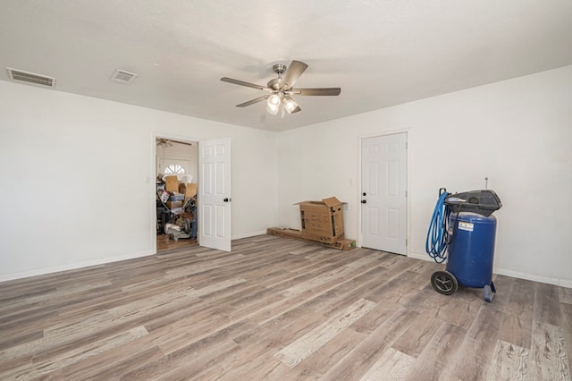 interior space featuring visible vents, baseboards, a ceiling fan, and wood finished floors