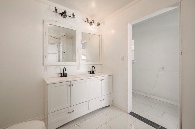 full bath featuring a sink, baseboards, toilet, and double vanity