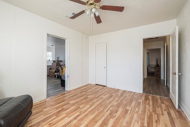 living area featuring light wood finished floors, visible vents, a ceiling fan, and baseboards