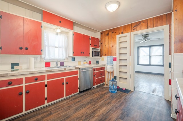 kitchen with red cabinetry, a sink, dark wood finished floors, appliances with stainless steel finishes, and a healthy amount of sunlight