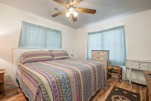 bedroom featuring ceiling fan, visible vents, and wood finished floors