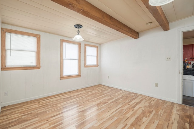 empty room with beam ceiling, baseboards, and wood finished floors