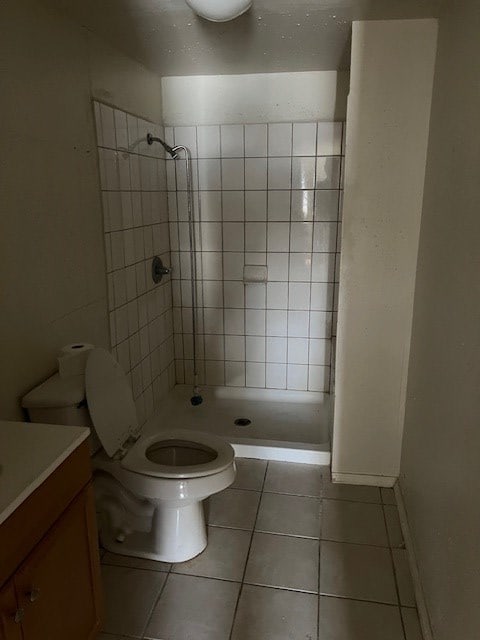 bathroom featuring tile patterned flooring, vanity, toilet, and a tile shower