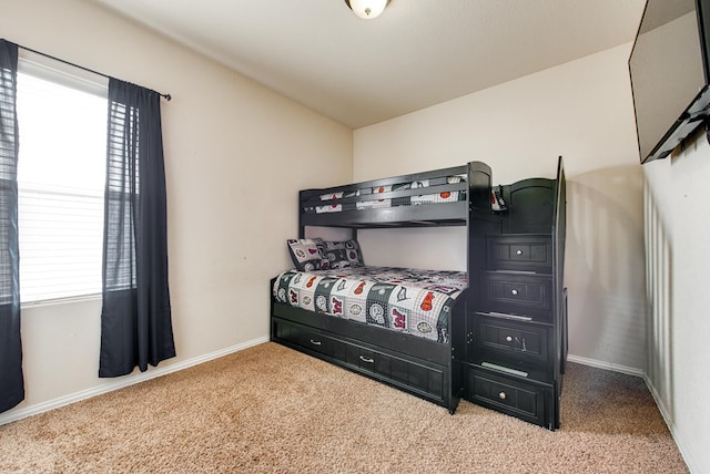 carpeted bedroom featuring multiple windows and baseboards