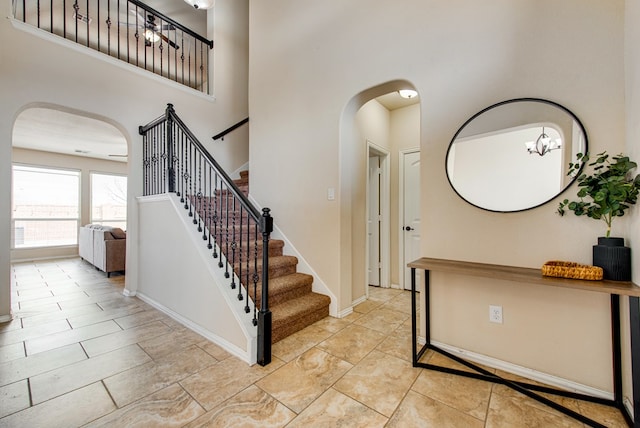 foyer entrance featuring arched walkways, baseboards, stairway, and a high ceiling