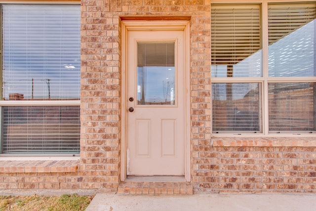 doorway to property featuring brick siding