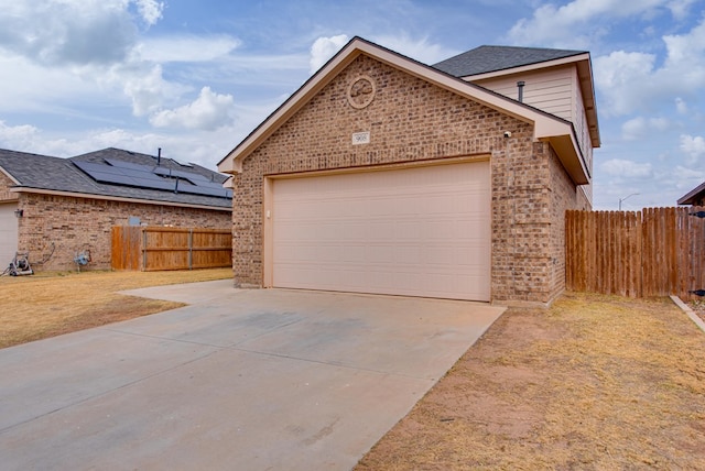 view of front of property featuring a garage, concrete driveway, brick siding, and fence