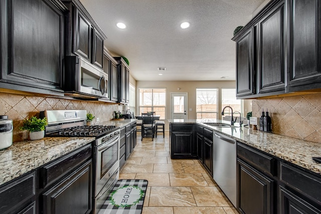 kitchen with stainless steel appliances, a sink, and dark cabinets