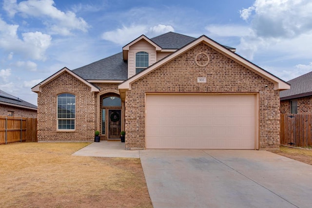 view of front of home featuring a garage, brick siding, fence, and driveway