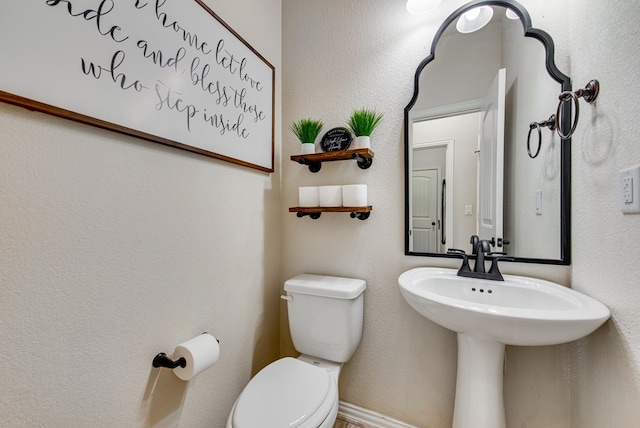 half bath featuring a textured wall and toilet