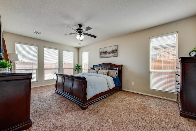 bedroom with a textured ceiling, carpet floors, visible vents, and baseboards