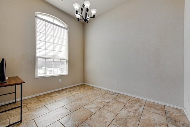 empty room with a chandelier and baseboards