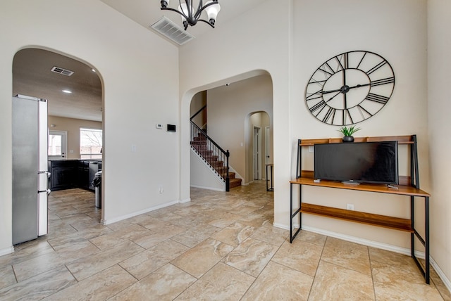 foyer featuring arched walkways, stairs, visible vents, and baseboards