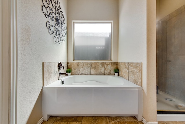 bathroom featuring a shower stall and a bath