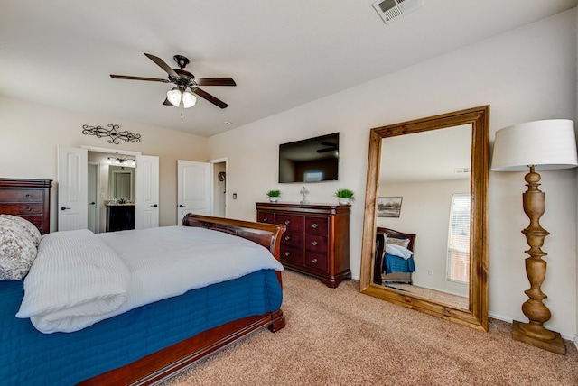 bedroom featuring ensuite bathroom, ceiling fan, light colored carpet, visible vents, and baseboards