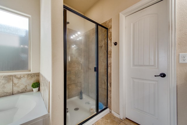 bathroom with a stall shower, a bath, and tile patterned floors