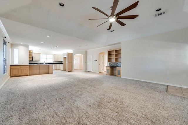 unfurnished living room featuring ceiling fan, baseboards, light carpet, recessed lighting, and arched walkways