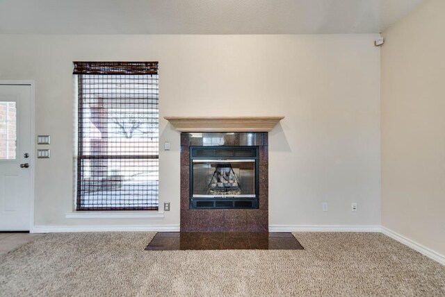 unfurnished living room featuring carpet flooring, a fireplace, and baseboards