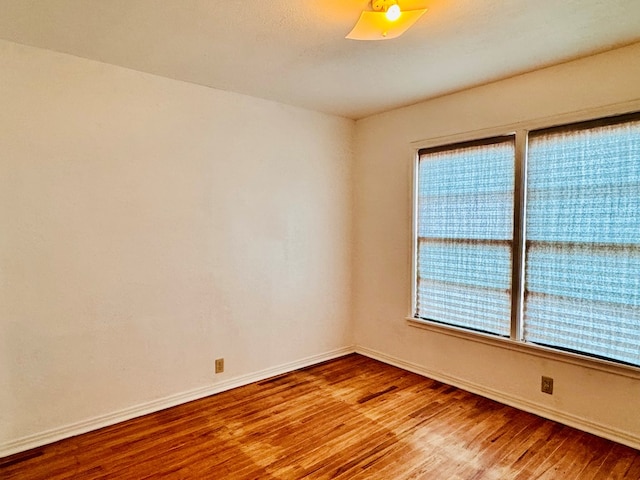 empty room with baseboards, a healthy amount of sunlight, and wood finished floors