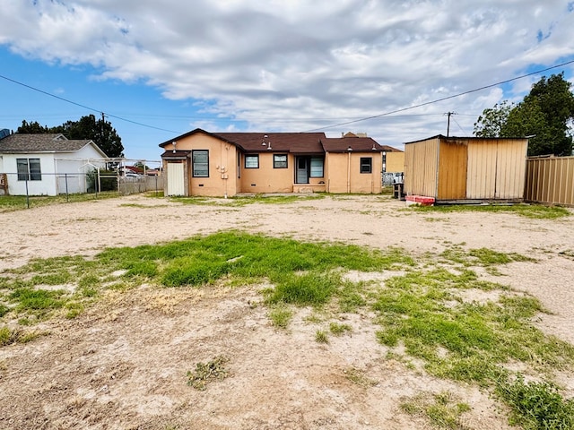 back of property featuring stucco siding, an outbuilding, fence, and a storage shed