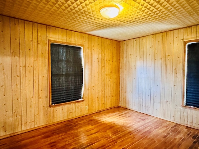 spare room featuring wooden walls and hardwood / wood-style floors