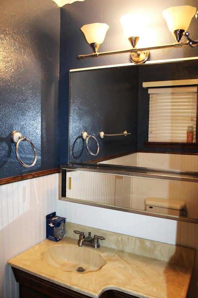 bathroom featuring vanity, toilet, and wood walls