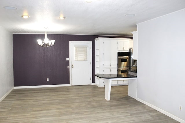 kitchen with white cabinetry, a kitchen breakfast bar, double oven, hardwood / wood-style floors, and decorative light fixtures