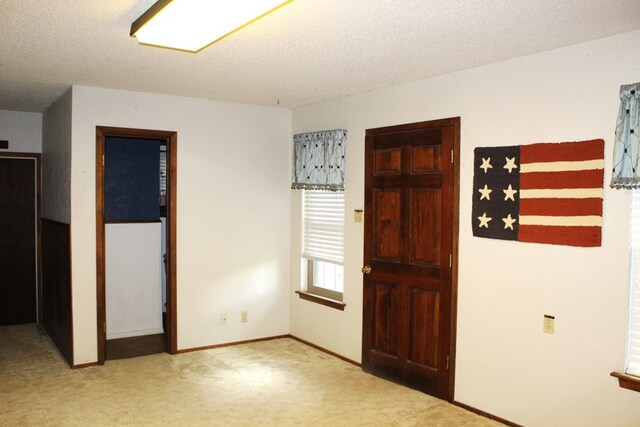 foyer entrance with light colored carpet and a textured ceiling