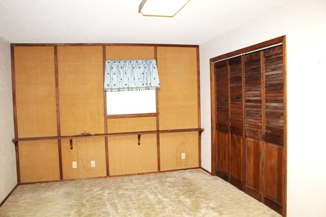 unfurnished bedroom featuring a textured ceiling, light colored carpet, and a closet