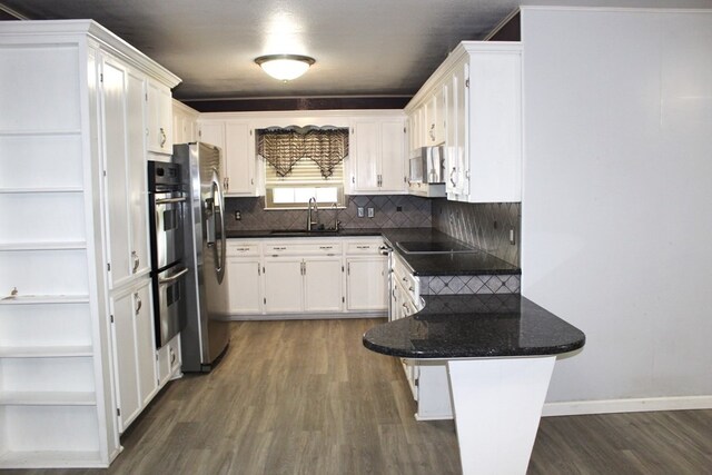 kitchen with decorative backsplash, stainless steel appliances, dark wood-type flooring, sink, and white cabinetry