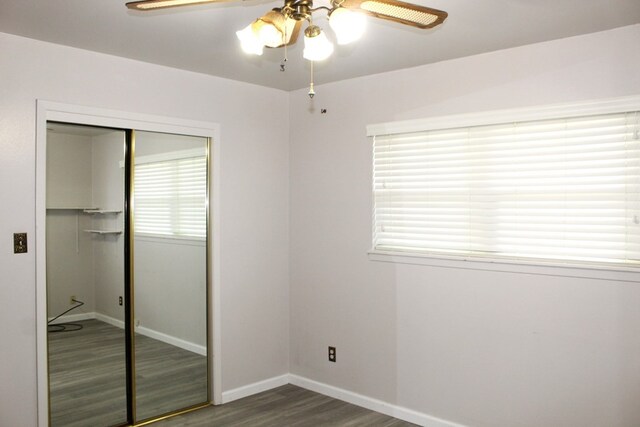 unfurnished bedroom with ceiling fan, a closet, and dark wood-type flooring