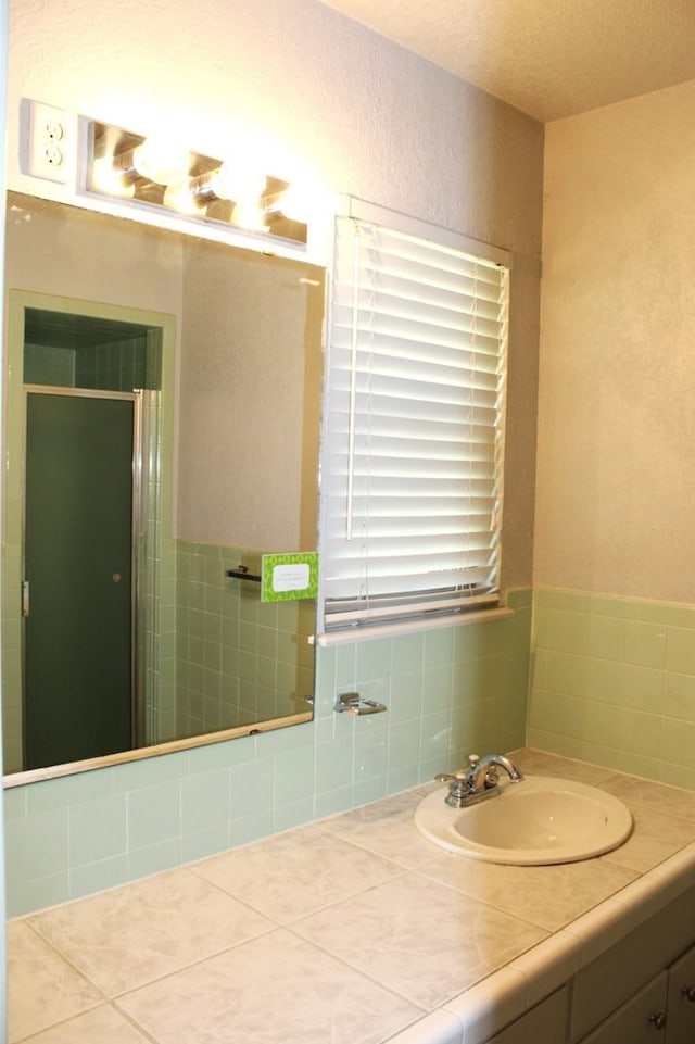 bathroom with tile patterned flooring, vanity, a shower with shower door, and a textured ceiling