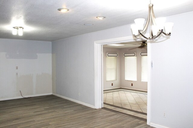 empty room featuring wood-type flooring, ceiling fan with notable chandelier, and a textured ceiling