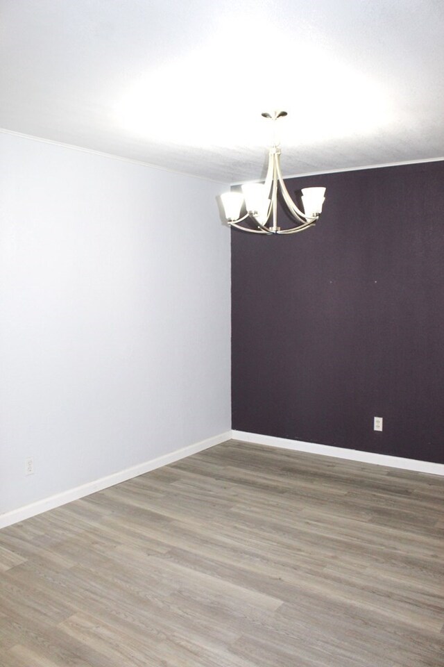 unfurnished dining area featuring wood-type flooring and an inviting chandelier