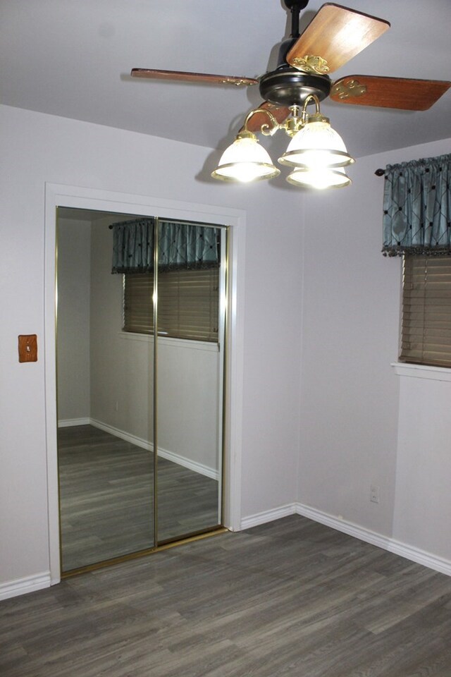 unfurnished bedroom with dark hardwood / wood-style floors, ceiling fan, and a closet