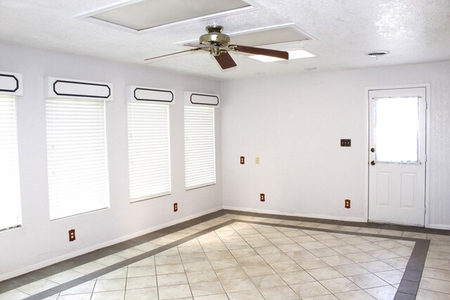 tiled empty room with ceiling fan and a textured ceiling