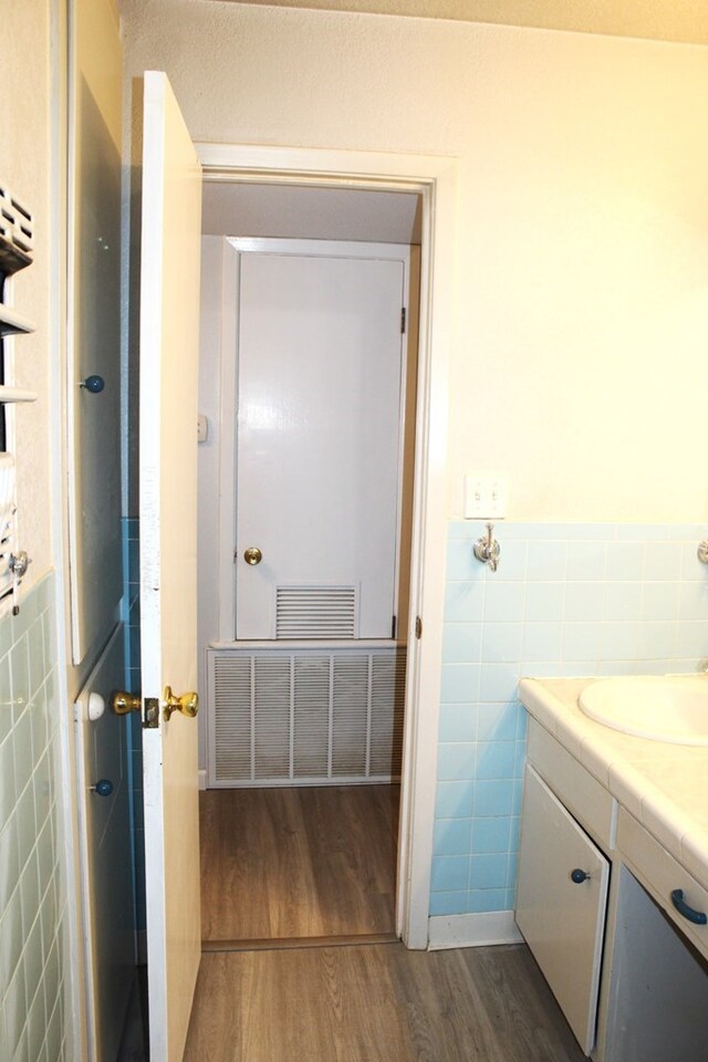 bathroom featuring vanity, wood-type flooring, and tile walls