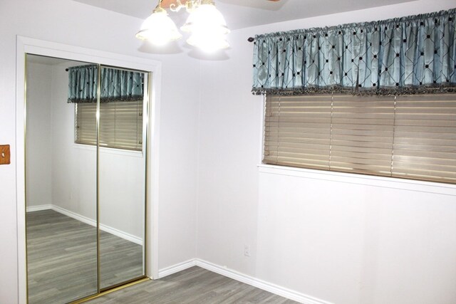 unfurnished bedroom featuring hardwood / wood-style floors, a closet, and a notable chandelier