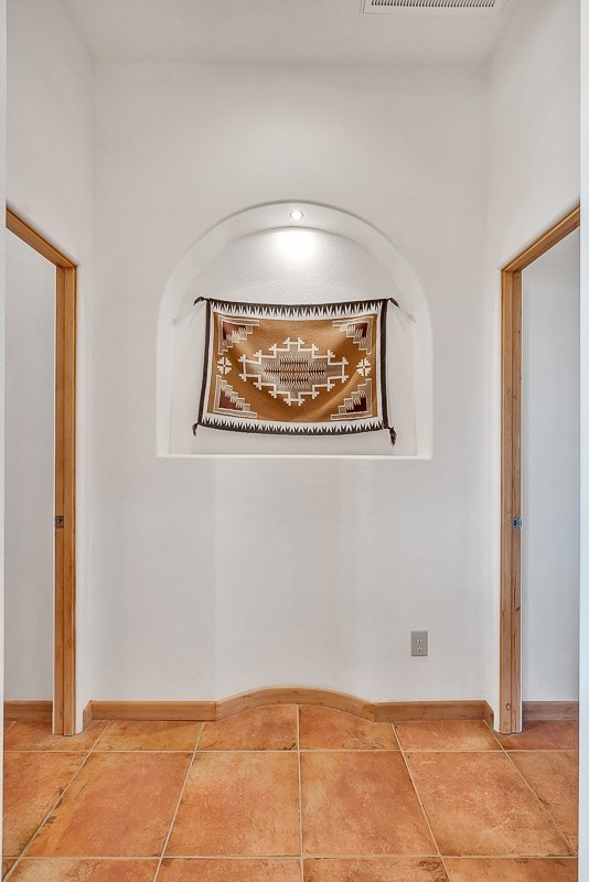 hallway featuring tile patterned flooring and baseboards