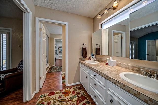 bathroom featuring hardwood / wood-style flooring, vanity, and a textured ceiling