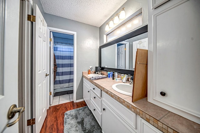 bathroom with wood-type flooring, a shower with shower curtain, a textured ceiling, and vanity