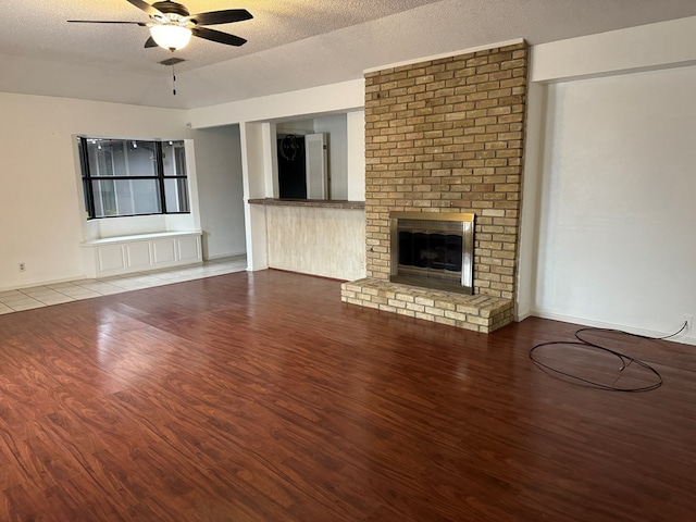 unfurnished living room featuring ceiling fan, a textured ceiling, a fireplace, and light hardwood / wood-style floors