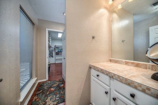 bathroom featuring hardwood / wood-style flooring, vanity, and a textured ceiling