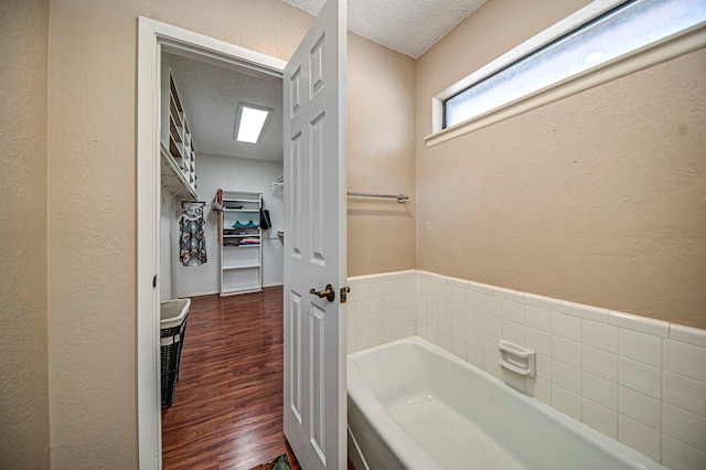 bathroom featuring hardwood / wood-style flooring, a bath, and a textured ceiling