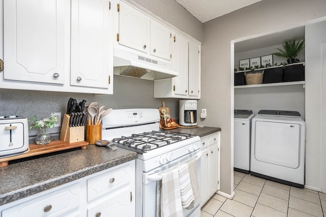 kitchen featuring white gas range oven, dark countertops, independent washer and dryer, under cabinet range hood, and white cabinetry