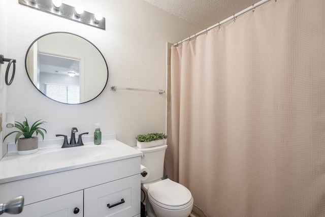 bathroom with a textured ceiling, curtained shower, vanity, and toilet