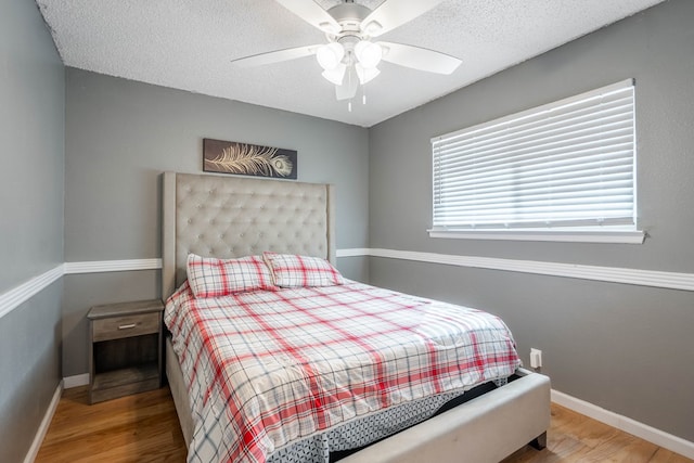 bedroom featuring a textured ceiling, wood finished floors, and baseboards