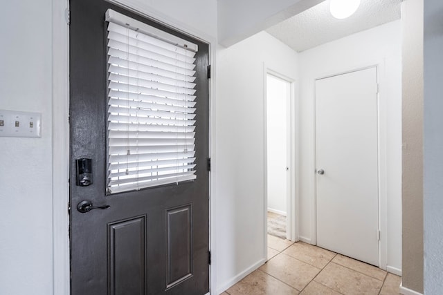 tiled entrance foyer featuring baseboards and a textured ceiling